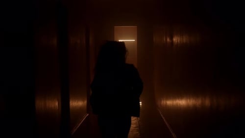 Silhouetted Figure Runs Through Dark, Glowing Corridor