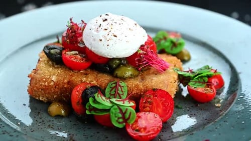 Tasty dish with fried food, fresh tomatoes, and herbs on a blue plate.