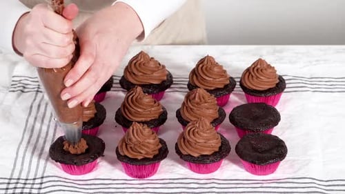 Schokoladen-Ganache-Zuckerguss auf Schokoladen-Cupcakes gießen