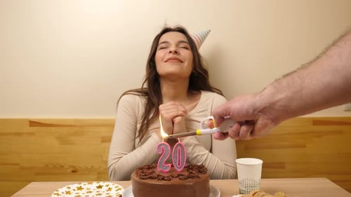 17sm. The girl is sitting in front of a table with a festive cake, in which a candle in the form of