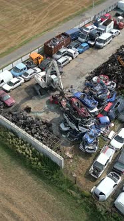 Grúa moviendo coches de chatarra en un depósito de chatarra