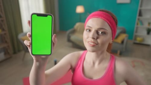 Portrait of a Redhaired Woman in the Living Room in Pink Sportswear After a Workout Close Up A Woman