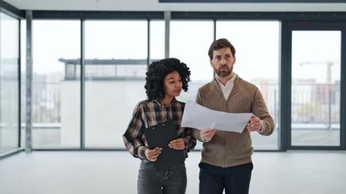 Business Colleagues Discuss Blueprints in Modern Office