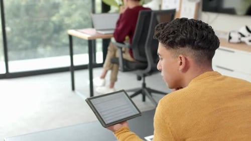 Utilisation d'une tablette, homme travaillant à domicile tandis que son partenaire travaille sur un ordinateur portable