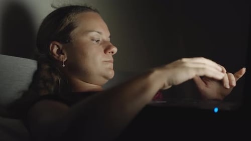Night, a young woman on the bed with a laptop. Close-up, zoom