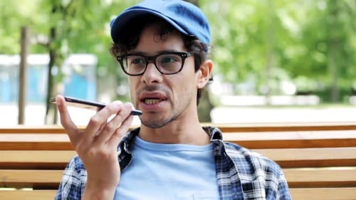 Man talking on speakerphone on city street using smartphone technology