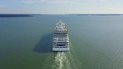Luxury cruise ship making way ahead in Finnish archipelago on departure. Aerial stern view.
