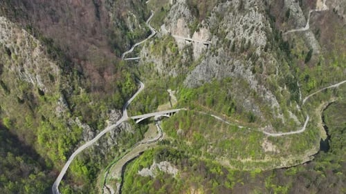 Winding mountain road through lush forest captured from above on a clear spring day