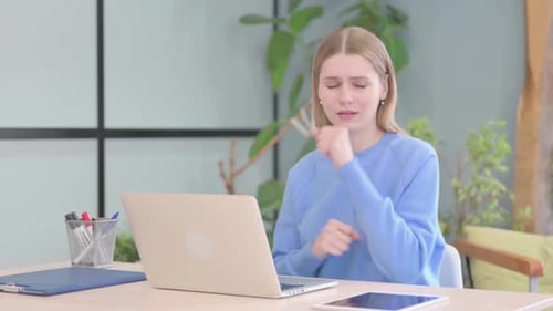 Young Woman Coughing While Working at Laptop