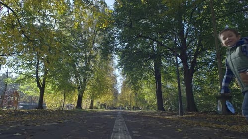 A Smiling Boy Child Walks with a Dog in Autumn in the Park