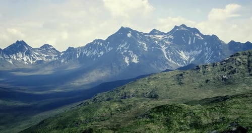 Majestic Snow Capped Mountains Rise Above Green Valleys in Bright Daylight