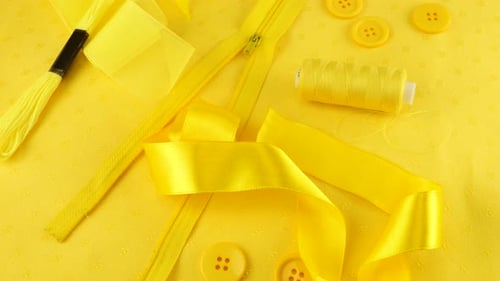 Top view onthe cotton fabric and various sewing accessories in yellow rotates on the showcase.