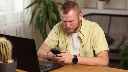 Businessman holding smartphone sitting in office, using cell phone mobile apps