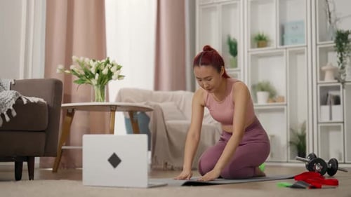 Mujer china entrenando sola en casa viendo un vídeo tutorial en la pantalla del ordenador portátil Entrenamiento deportivo en línea