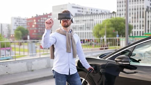 Man Charging Electric Car with VR Headset