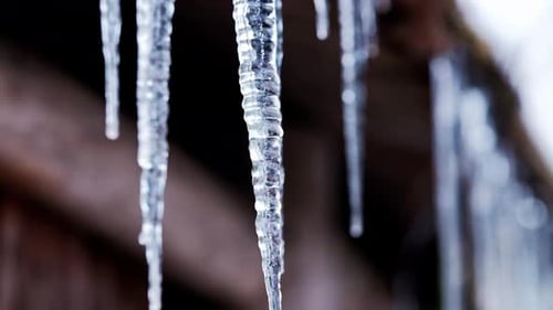 Wunderschöne Eiszapfen, die wie Kristalle aussehen, die sich im Winter auf einer Holzhütte gebildet haben