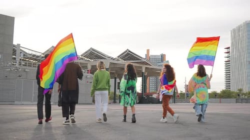 Young Adults Walking with Rainbow Flags in City