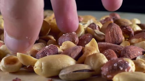 Close Up of Hand Picking Assorted Nuts