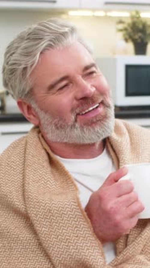 Man with Blanket Enjoying Hot Drink at Home