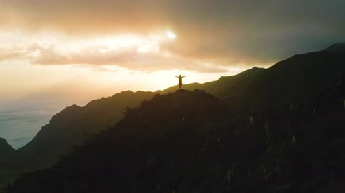 Alone Girl Stands on Top of Rock Mountain Ocean Background at Sunset