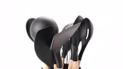 A set of black kitchen utensils including a spoon, spatula, and fork