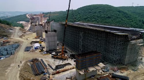 Construction d'un viaduc avec coffrage et grues dans une zone forestière