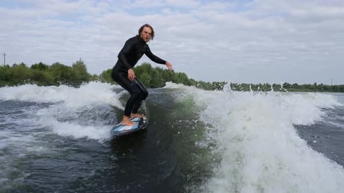 Man Wakesurfing on a Wake Created by a Boat