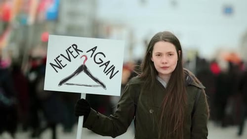 Woman Protests with Sign in an Urban Setting