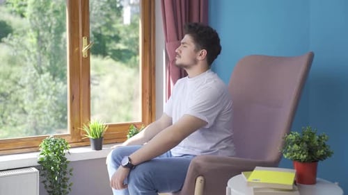 Young Adult Relaxing in Armchair by Window