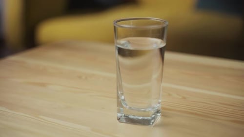 Hand Holding Pills With a Glass of Water