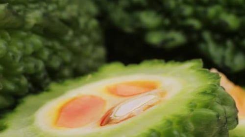 Une gourde amère, un légume souvent utilisé comme ingrédient en cuisine, est posée sur une table en bois.
