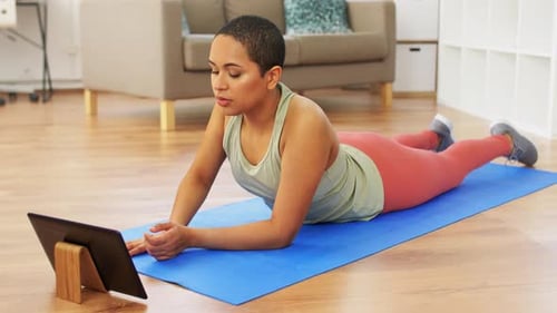 Woman Follows Exercise Routine on Tablet at Home