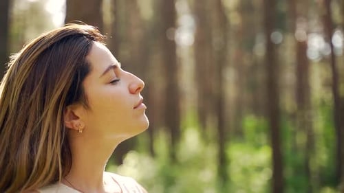Close up portrait of a pretty young woman breathes fresh air into her full chest in the middle