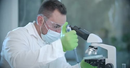 Scientist Analyzing Sample Under Microscope in Laboratory