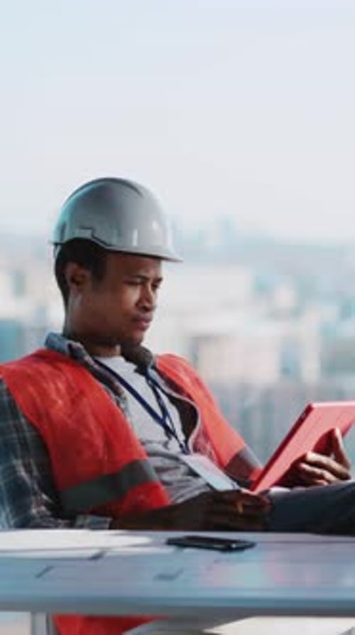 Relaxed African Young Business Civil Engineer Foreman Builder Sitting in Comfort Pose at Table
