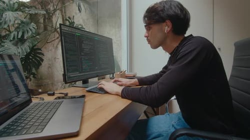 Concentrated Programmer Writing Code on Computer in Home Office