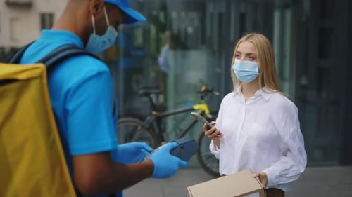 Multiracial Courier Delivers the Package to the Woman Client The Female Pays for the Package Online