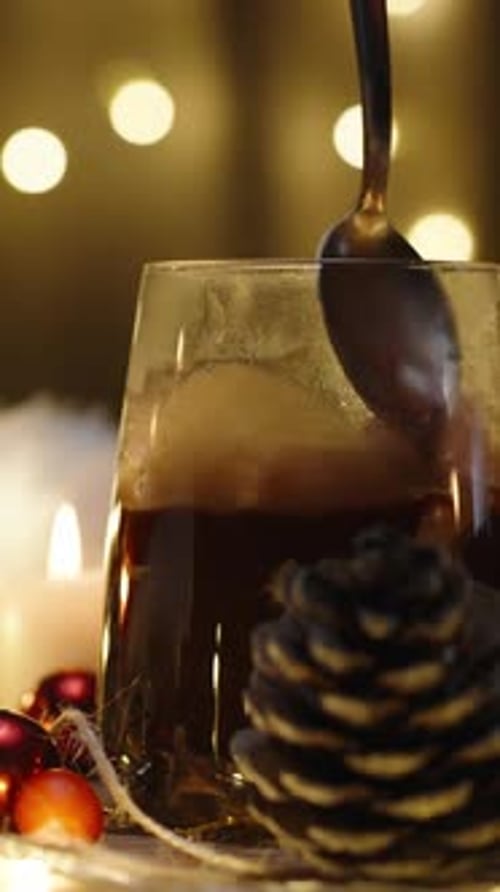 Vertical video. I stir marshmallows in cocoa, hot chocolate on the background of a garland of lights