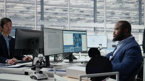 Examining Microchip Circuit Layouts Computer Monitor and Man in Factory Office