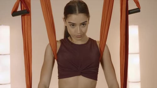 Sporty young woman practices yoga with hammock indoors at fly yoga studio in slow motion