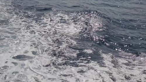 Sea waves formed in the wake of a boat floating on the waters.