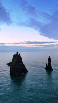 Sharp rocks stick out from the waterscape. Sea-gulls fly around the ...