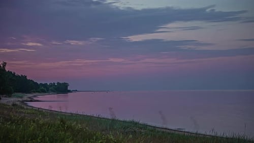 Wolken überqueren den Himmel bei Sonnenuntergang über dem ruhigen Ozean - Weitwinkel-Zeitraffer
