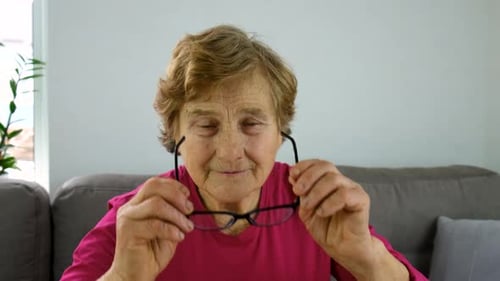 Senior Woman Puts On Her Glasses
