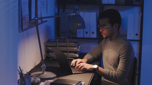 Developer Working on Laptop In Dark Office