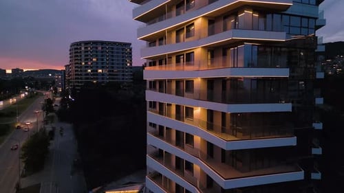 Modern Residential Building with Glass Balconies and LED Lighting at Sunset Urban Architecture and