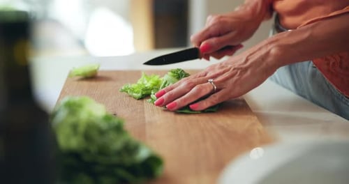 Woman cutting lettuce on chopping board in kitchen
