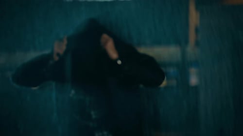 Young Caucasian Man Wearing in a Square Shirt is Using His Jeans Coat as a Raincoat. Scene is Shot