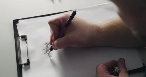 Close up of a man drawing an projecting a new ring design on a white paper. Concept: designer, gol