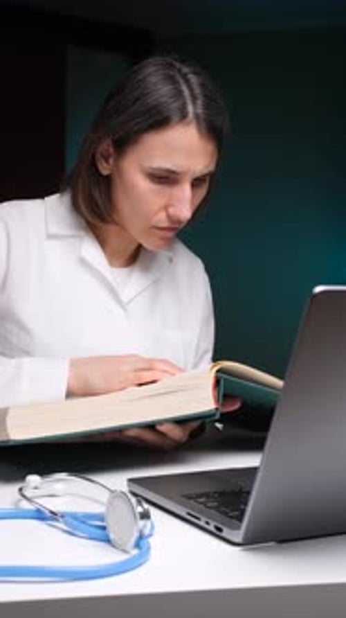 Vertical Video Doctor Studying Medical Book and Using Laptop for Research
